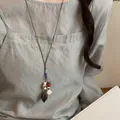 Close-up detail of a handmade forest-style plant acorn pendant necklace on a linen dress - Plant Seed Style (2#) / Brown