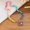 Primo piano di una collana di perle colorate con un ciondolo a fiore viola trasparente - Fiore Colorato (HN12332) / Viola