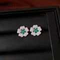 Macro view of flower-shaped stud earrings featuring green gemstones and white zircon - Stud Earrings / Silver-Green
