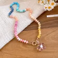 Primo piano di una collana di perle colorate con ciondolo a fiore in vetro e chiusura dorata. - Fiore Colorato (HN12332) / Rosa