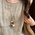 Detail view of a Mori style handmade woven necklace with plant acorn and wooden charms. - Acorn Wood Lotus Style (7#) / Brown