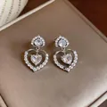 Macro detail of elegant silver-tone heart drop earrings with sparkling heart-shaped zircon stones - Silver
