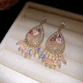 Detailopname van boho oorbellen met strass en iriserende kralenkwastjes in juwelendoos. - Roze