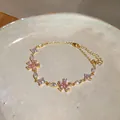 Exquisite close-up detail of a gold chain bracelet with pink and clear zircon flowers - Pink