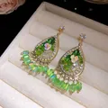 Detail van bohemien druppeloorbellen met groene kristallen kwastjes en bloemen. - Groen