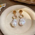 Close-up of French Baroque irregular pearl drop earrings on a vintage tray. - Silver Pin-Gold-White