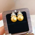 Detail shot of elegant golden pearl earrings with crown-shaped zircon embellishment - Champagne