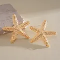 Detailed macro view of textured gold-toned starfish stud earrings on a natural stone - Gold Starfish Granular Texture Style (7#)