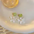 Dettaglio ravvicinato di orecchini stile foresta con perla verde e petali bianchi traslucidi - Bianco Verde