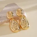 Detail shot of vintage gold-finished oval drop earrings with artistic relief design. - Gold Round Ear Relief Oval Design (12#)