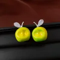 Detailansicht grüner Apfelohrringe mit funkelnden Kristallblättern auf elegantem dunklem Leder - Apfel Ohrstecker / Silberner Ohrstecker - Silber - Grün