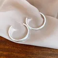 Vista dettagliata di orecchini a perno minimalisti a forma di C in argento spazzolato. - Argento