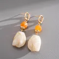 Detailed macro shot of vintage resin earrings featuring irregular marble drops and orange beads - Beige