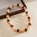 Detailed view of an acrylic marbled bead necklace in peach and amber tones. - Pink Brown Marbling