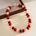 Detail view of a marbled acrylic bead necklace with red and pink swirled patterns. - Red Pink Orange Marbling