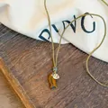 Close-up of artistic stone fish pendant and engraved heart charm on woven rope necklace - Brown