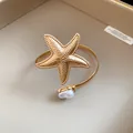 Detailed close-up showing a vintage gold starfish armlet accented with a white pearl. - Starfish Pearl / Gold