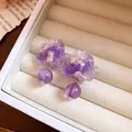 Primo piano di orecchini a fiore in resina viola in un portagioie beige crema. - Viola