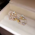 Close-up of 18k gold plated butterfly star stud earrings with pearls and cubic zirconia. - Gold