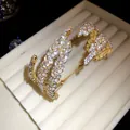 Macro detail of a triple-layer leaf open cuff bracelet adorned with sparkling zircons - Gold