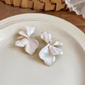 Detailed macro shot of oversized white enamel flower stud earrings with gold edges - Steel Post Flower Studs / White