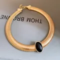 Close-up of vintage gold metallic choker with central black oval resin stone inlay. - Gold-Black