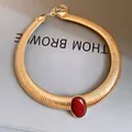 Close-up of elegant vintage gold metal choker featuring a red oval resin stone detail - Gold-Red