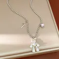 Detailed close-up of a silver necklace featuring a pearlescent bear and pink heart charm - Silver
