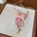 Detail view of a pink fabric flower necklace with elegant beaded tassels on a linen tray - Necklace / Pink