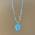 Detailansicht einer bunten gewebten Halskette mit blauem Blumenanhänger Motiv - Blau