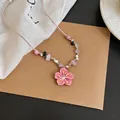 Detailed view of a pink cherry blossom pendant necklace with colorful beads on a pink cord - Pink