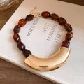 Detail shot of a vintage acrylic beaded necklace featuring a curved gold metal pendant (84 chars) - Brown