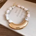 Close-up of marbled acrylic beads and polished gold crescent pendant on a vintage necklace - White