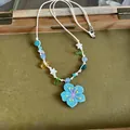 Detailed view of a colorful dopamine necklace with a blue flower pendant and star beads. - Blue