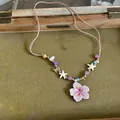 Detail shot of a dopamine-style necklace featuring a large purple flower pendant and colorful beads - Purple