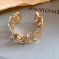 Detail shot of a gold open cuff bracelet with irregular swirl and oval patterns. - Spiral Hollow Style (HB5607) / Gold