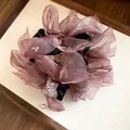 Gros plan d'un chouchou en mousseline rose avec des détails pailletés sur un plateau. - Violet