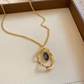 Close-up of vintage gold twisted pendant necklace with oval blue gemstone detail - Necklace