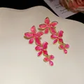 Detailansicht der rosa Emaille-Blumen-Ohrhänger mit goldenem Finish auf einem Display. - Oberteile / Rosa