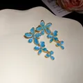 Exquisite Detailansicht blauer Emaille-Blumenohrringe mit edlem goldenem Designrand - Oberteile / Blau