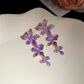 Nahaufnahme eleganter lila Blumen-Ohrringe mit goldfarbenem Rand und Silbernadeln. - Oberteile / Lila