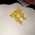 Detailaufnahme der gelben Emaille-Blumen-Ohrhänger mit goldenem Rand auf Teller - Oberteile / Gelb