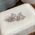 Detailed macro shot of elegant bow-shaped pearl stud earrings on white velvet - Hollow Bowknot Artificial Pearl Pendant Style / Silver