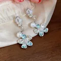 Detailed macro shot of the light blue crystal flower and pearl clip-on earrings - Silver-Blue