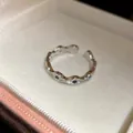 Détail d'une bague minimaliste en argent à bande ondulée avec zircons bleus - Style Étoilé Ondulé / Argent