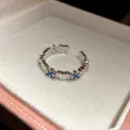 Vue détaillée d'une bague ouverte en cœur argenté avec zircons bleus en boîte cadeau - Figurine Bleue avec Cœur / Argent