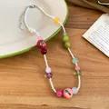 Detailed macro shot of resin fruit beads and pearls on a French style necklace. - White Green Red