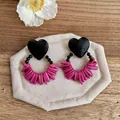 Macro detail of retro heart-shaped wooden earrings with vibrant pink coral-style beads. - Black - Rose Red