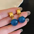 Macro-opname van vintage gouden oorbellen met grote blauwe bolvormige hangers van hars - Blauw