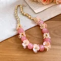 Close-up of pink acrylic beads and gold flower accents on a vacation style necklace. - Pink